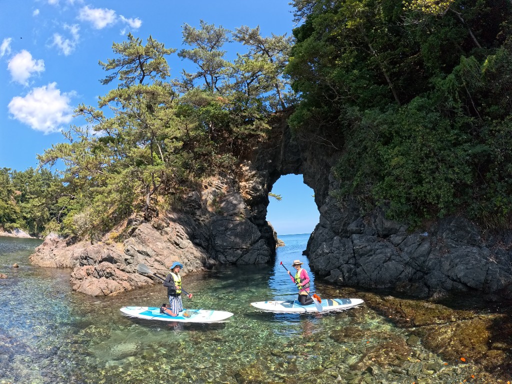 洞窟の入口をSUPで進む三人