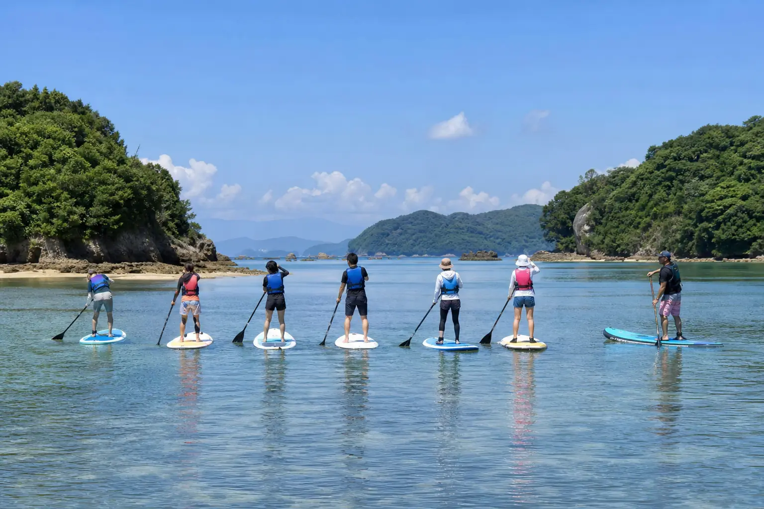 浅瀬を横一列に進むSUPと、並走する指導者(撮影イメージ)